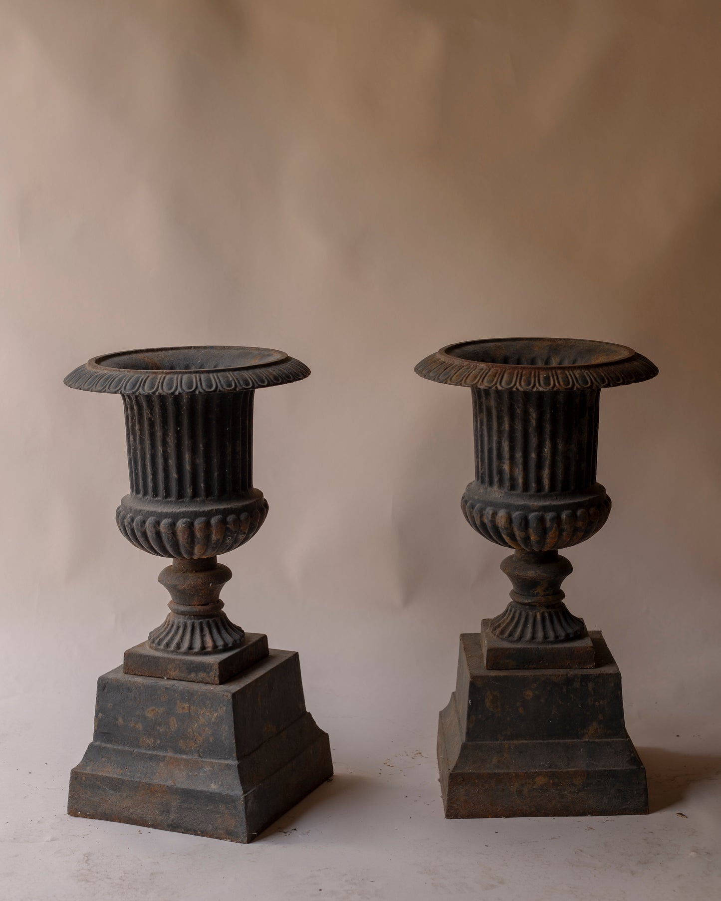 Pair of grey cast iron urns with plinth