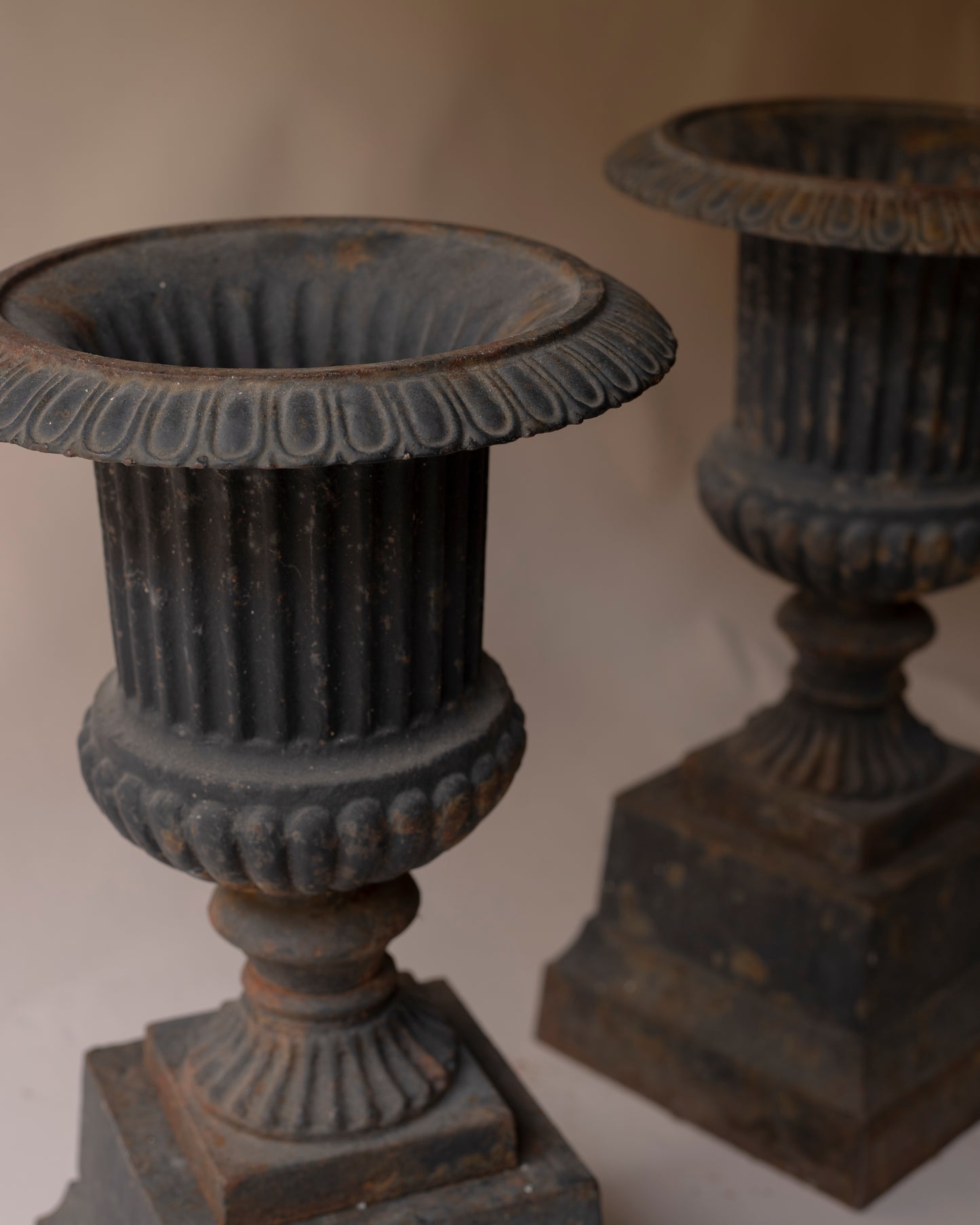 Pair of grey cast iron urns with plinth